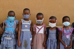 FILE - Children wearing face masks gather outside their classroom at a school in Abidjan, Ivory Coast, May 25, 2020.