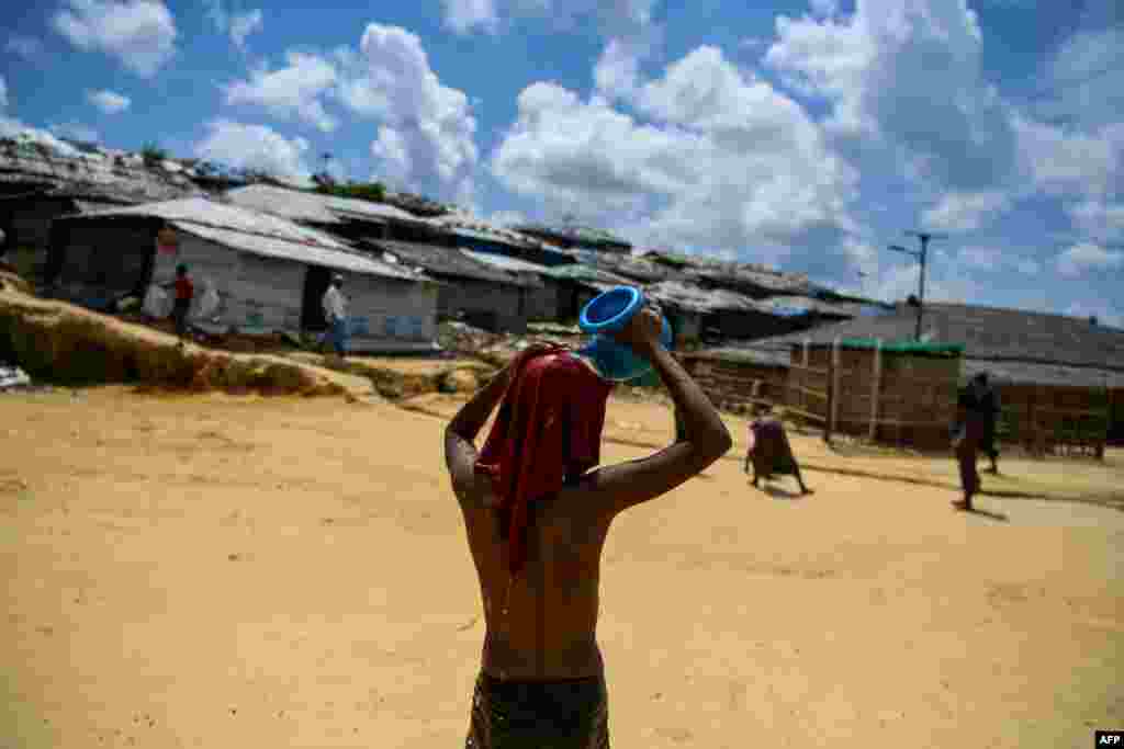 Rohingya refugee boy pours water on himself to escape the heat in Kutupalong camp in Ukhia.