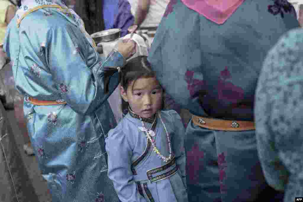 A girl wearing a traditional Mongolian costume waits with her mother during a speech from presidential candidate Battulga Khaltmaa from the Mongolian Democracy Party, during a rally in Ulaanbaatar. On June 26, Mongolians will elect a president from among three candidates.