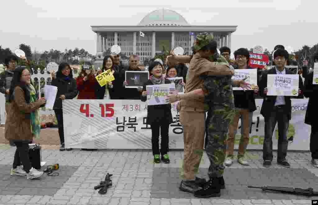 2013年4月15日,分别身穿朝鲜(左)和韩国军服的反战活动人士参加“军费开支全球行动日”活动,在首尔的国民议会前集会并互相拥抱。