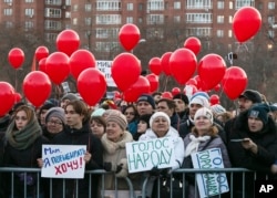 FILE - People hold red balloons and signs protesting an initiative to end mayoral elections in Yekaterinburg, Russia, April 2, 2018. One of the signs reads 'Mom, I want to vote", while the other, in a Russian word play, can mean both "Voice of the people" and "People deserve a voice.