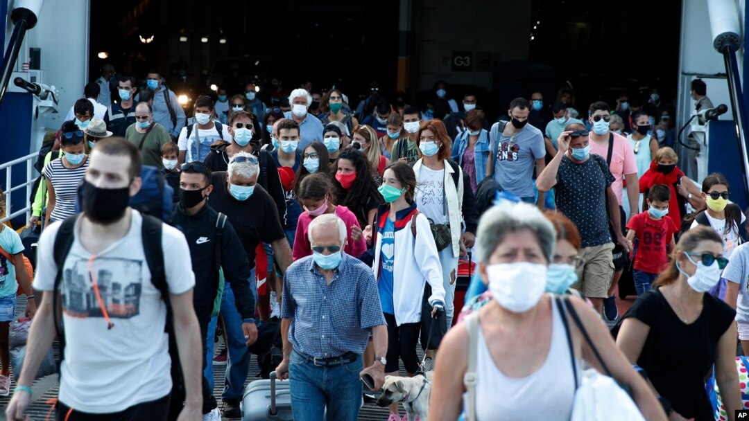 Travellers wearing face masks against the spread of the new coronavirus, disembark from a ferry at the port of Piraeus, near Athens, Aug. 20, 2020.