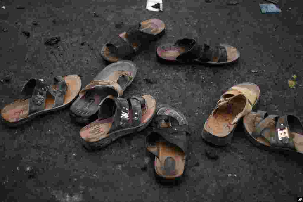 Sandals with blood stains are seen at the site of a suicide bombing as Yemeni security officials gather debris in Sana'a, Oct. 9, 2014.