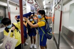 香港小学生在“全民国家安全教育日“会场内手持模仿机关枪在一个布置成地铁车厢的展览内游玩