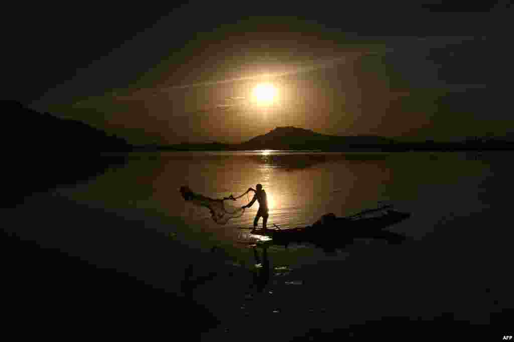 A fisherman casts his net from a boat in Dal Lake as the sun sets in Srinagar, Indian-controlled Kashmir.