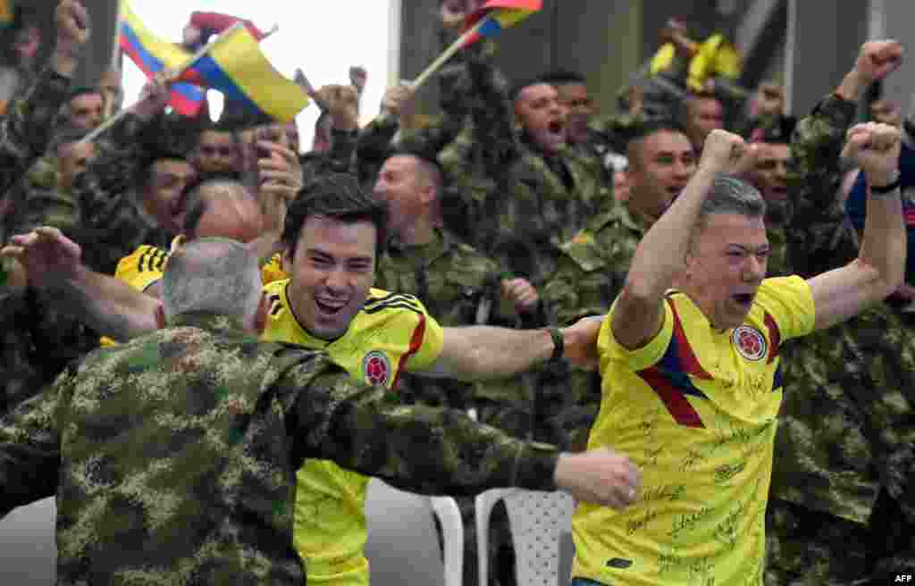 Colombian President Juan Manuel Santos (R) along with his son Esteban (C) and members of the Colombian army celebrate as they follow on a screen the FIFA World Cup match between Colombia and Senegal, at a military base in Tolemaida, Colombia.