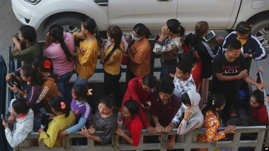 Cambodian garment factory workers ride on the back of a truck as they head to work outside Phnom Penh, Cambodia, Sept. 22, 2020.