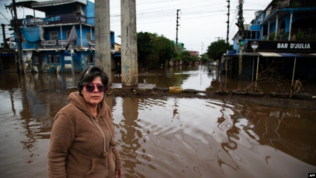 FILE - Orioplina Bechiln, a street barbecue vendor, walks along a flooded street around the Arena do Gremio stadium in Porto Alegre, Rio Grande do Sul State, Brazil, on May 29, 2024.