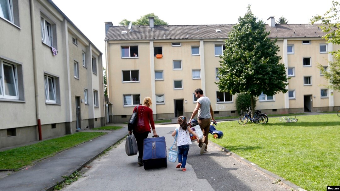 Four-year-old refugee Lilas from Syria and her parents walk to their refugee home in Muelheim an der Ruhr, Germany, after receiving articles for daily use prepared by donors at a distribution center, Aug, 20, 2015. 
