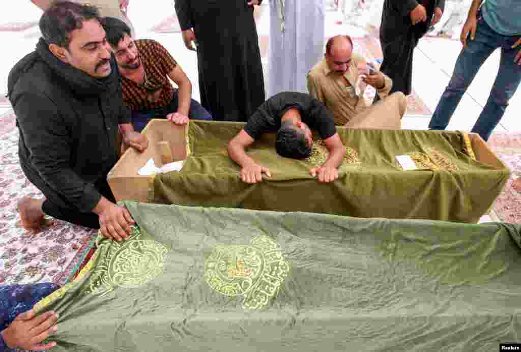 Mourners react next to the coffins of a victim, who was killed in a fire that broke out at al-Hussain coronavirus hospital in Nassiriya, during a funeral in Najaf, Iraq.
