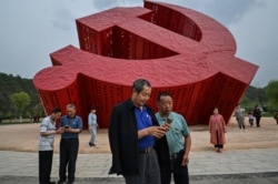 中国民众在延安附近的南泥湾树立的中共镰刀斧子党徽雕塑前拍照。（2021年5月11日）