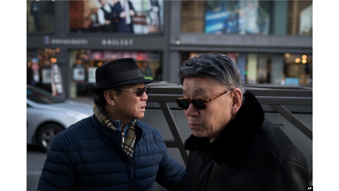 Song Hong, left, walks with his childhood friend Choi Kyu-Sik in downtown Gangneung, South Korea, Feb. 12, 2018.