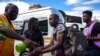 FILE - A taxi marshall wearing a face mask sprays sanitizer on passengers' hands to protect against coronavirus, at a minibus taxi station in Johannesburg, South Africa, March 26, 2020.