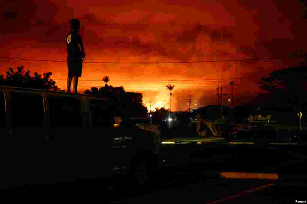 Darryl Sumiki, 52, of Hilo, watches as lava lights up the sky above Pahoa during ongoing eruptions of the Kilauea Volcano in Hawaii, June 2, 2018.
