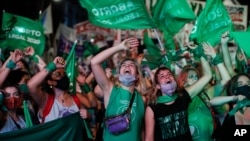 Abortion-rights activists watch live video streaming of lawmakers in session, outside Congress in Buenos Aires, Argentina, Dec. 30, 2020, as Congress approved a bill that legalize abortion in Argentina.