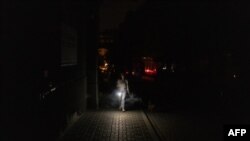 Жінка у Києві йде темрявою під час часткового відключення електроенергії, що спричинено російськими ударами по енергетичній інфраструктурі, 5 червня 2024 р. Roman PILIPEY/AFP