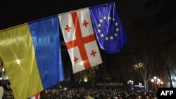 Демонстранти йдуть біля прапорів України, Грузії та Європи під час акції протесту проти рішення уряду відкласти переговори про вступ до ЄС до 2028 року, Тбілісі, 30 листопада 2024 року. Giorgi ARJEVANIDZE/AFP