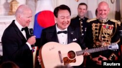 美国总统拜登在白宫赠送韩国总统尹锡悦一把吉他。（2023年4月26日）