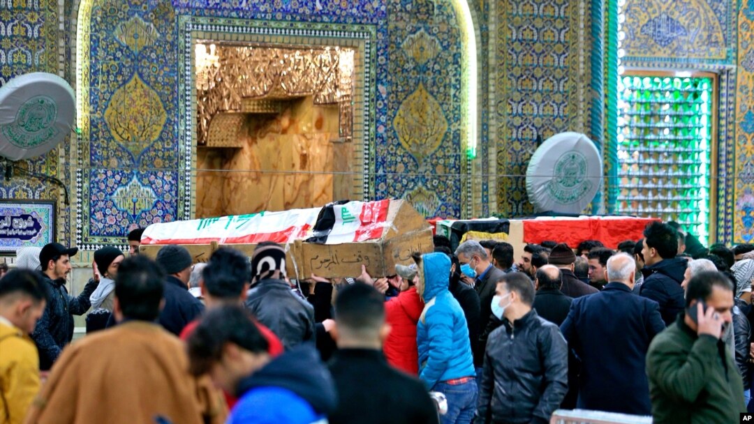 Mourners carry flag-draped coffins of suicide bomb victims at the Imam Ali shrine in Najaf, Iraq, Jan. 21, 2021.