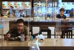 台北餐馆在新冠疫情期间采取措施，吃午餐的顾客之间隔着塑料屏并保持距离。（2021年5月12日）