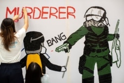 一名香港反送中抗议者在手绘一幅全副武装的蒙面港警开枪实弹射击一名抗议学生情景的壁画。（2019年10月2日）