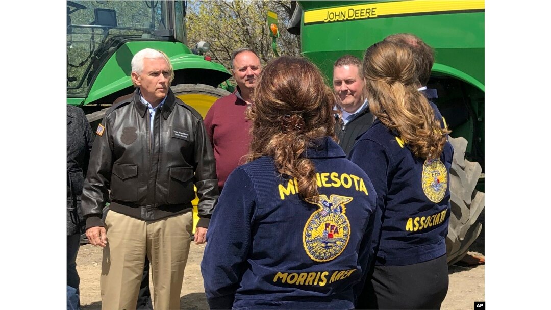 Vice President Mike Pence, left, visits with farmers and future farmers as he tours the R & J Johnson Farms in Glyndon, Minn., May 9, 2019, to talk about the Trump administration's trade agreement with Canada and Mexico.