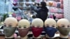 FILE - A vendor arranges a shelf full of masks as he waits for customers in a shopping mall in Yiwu, Zhejiang province, China.