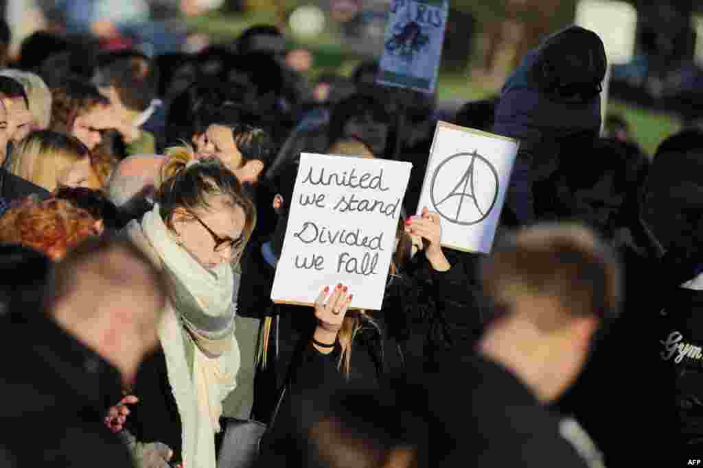 A woman holds the "#PeaceForParis" logo and a sign reading "United we stand, Divided we fall" on Nov. 15, 2015 in Caen during a demonstration in front of the Memorial of Caen in tribute to the victims of the Paris attacks.