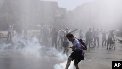 A protester kicks a tear gas canister during clashes with police in Santiago, Chile, Oct. 20, 2019.