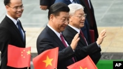 资料照：中共总书记、中国国家主席习近平与越共总书记阮富仲向举着中越国旗的欢迎人士挥手致意。(2017年11月12日)