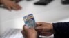 Una mujer recibe dinero de un empleado en el centro de Ciudad de México, el 17 de julio de 2020, en medio de la pandemia del nuevo coronavirus. 