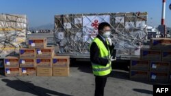 希腊雅典国际机场的一名工人站在从中国运抵的口罩等抗疫防护用品。（2020年3月21日）