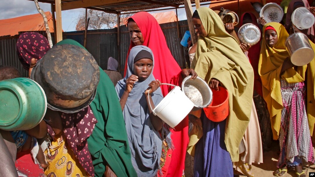 FILE - Women who fled drought queue to receive food at a camp for internally displaced persons, in the Daynile neighborhood on the outskirts of the capital Mogadishu, Somalia, May 18, 2019. 