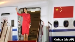 In this photo released by China's Xinhua News Agency, Huawei CFO Meng Wanzhou waves as she steps out of an airplane after arriving at Shenzhen Bao'an International Airport in Shenzhen in southern China's Guangdong Province, Saturday, Sept. 25, 2021.
