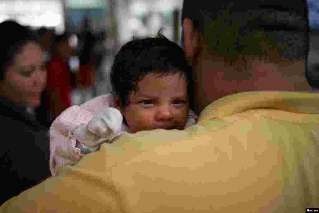An undocumented immigrant father from Honduras and his infant daughter are released from detention with other families at a bus depot in McAllen, Texas, U.S., July 26, 2018.
