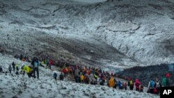 People watch and take photos as lava flows from an eruption of a volcano on the Reykjanes Peninsula in southwestern Iceland on March 24, 2021.