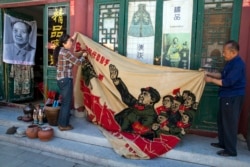 北京商贩正在展示一面画有中国前领导人毛泽东在文革时期的宣传旗。（2016年5月16日）
