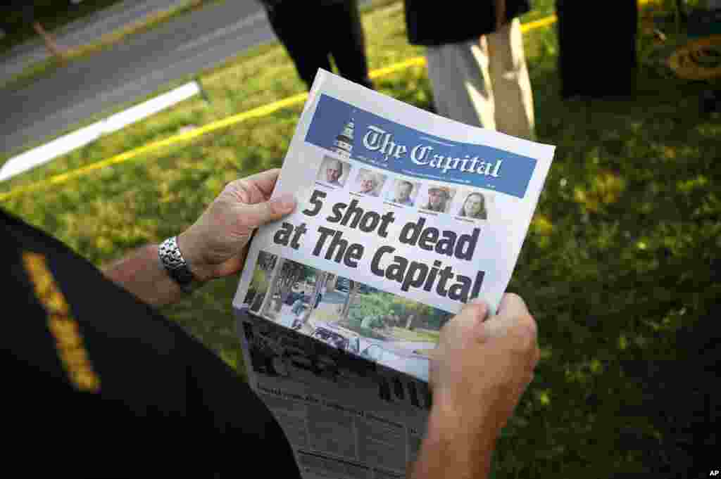 Steve Schuh, county executive of Anne Arundel County, holds a copy of The Capital Gazette near the scene of a shooting at the newspaper's office in Annapolis, Md. A man armed with smoke grenades and a shotgun attacked journalists in the building Thursday, killing several people before police quickly stormed the building and arrested him, police and witnesses said.