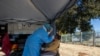 A woman has a sample collected for coronavirus testing during the screening and testing campaign aimed to combat the spread of COVID-19, in Eldorado Park outside of Johannesburg, South Africa, Aug. 3, 2020.