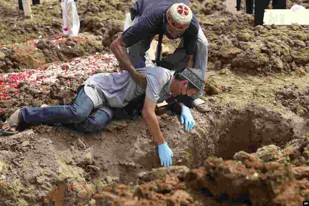 A man weeps on the ground during the burial of a relative who died of COVID-19 at Rorotan Cemetery in Jakarta, Indonesia.