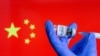 中国国旗前贴有新冠病毒疫苗标签的小瓶子
