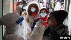 河北省石家庄一名身穿防护服的医护人员在给居民做病毒核酸检测。（2021年1月6日）