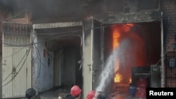 Residents gather while firefighters try to extinguish a fire at a shoe factory in Lahore, Sept. 11, 2012. 