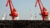 FILE - Piles of steel pipes to be exported are seen in front of cranes at a port in Lianyungang, Jiangsu province, March 7, 2015. 