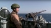 FILE - A Russian seaman stands next to a machine gun on the Russian missile cruiser Moskva, near the shore of Syria’s province of Latakia, Syria, Nov. 27, 2015.