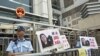 A policeman stands guard next to portraits of Chinese journalist Gao Yu during a demonstration calling for Gao's release from a prison in China, outside the Chinese liaison office in Hong Kong, April 17, 2015.