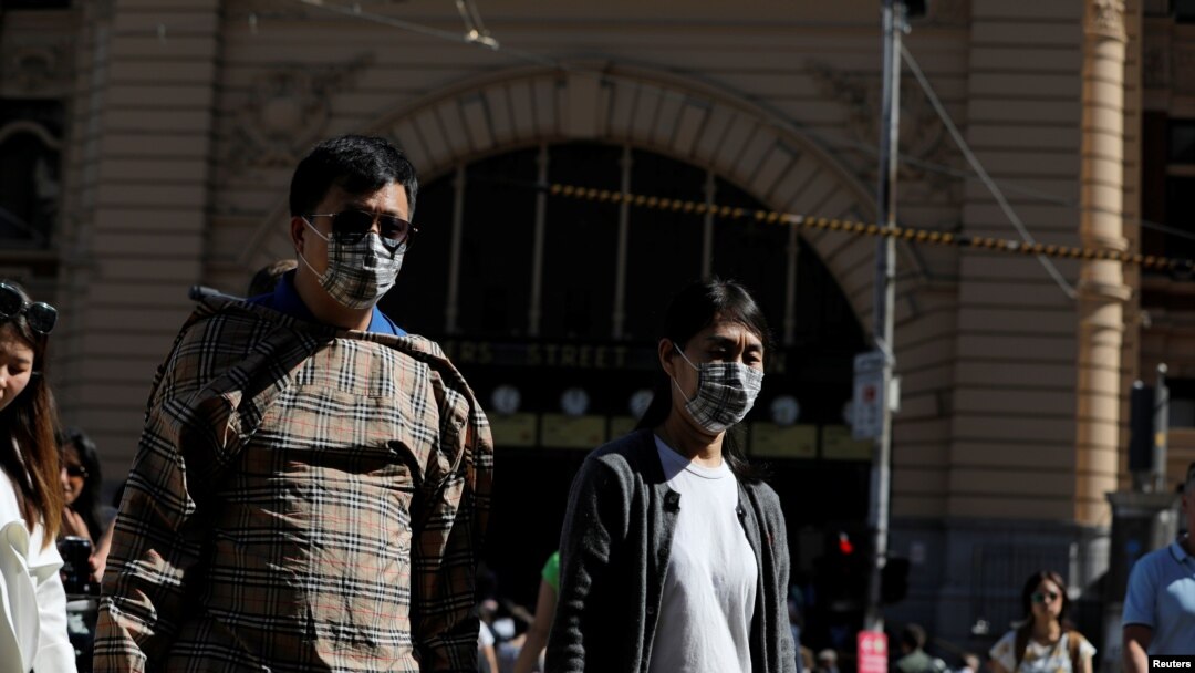 People wearing face masks walk by Flinders Street Station after cases of the coronavirus were confirmed in Melbourne, Victoria, Australia, Jan. 29, 2020.