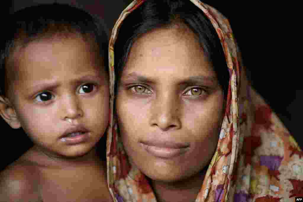 19-year-old Rohingya refugee Dola Banu poses for a photo with her son in the entrance to her shelter at the Thangkhali refugee camp near Cox's Bazar.