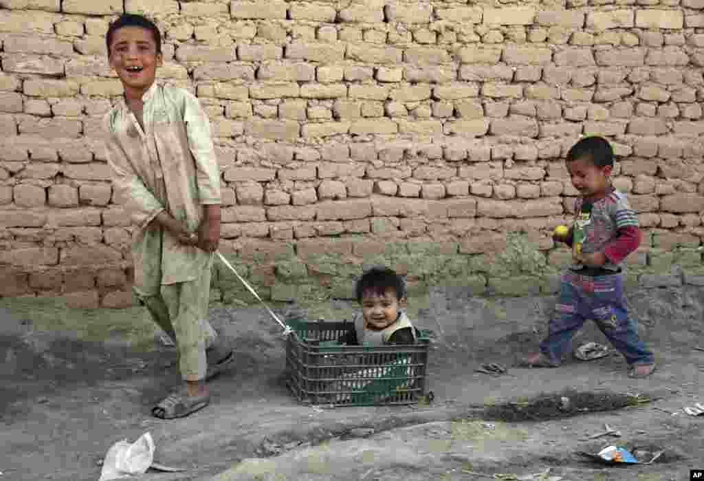 A boy pulls his little brother in a basket on the outskirts of Kabul, Afghanistan.