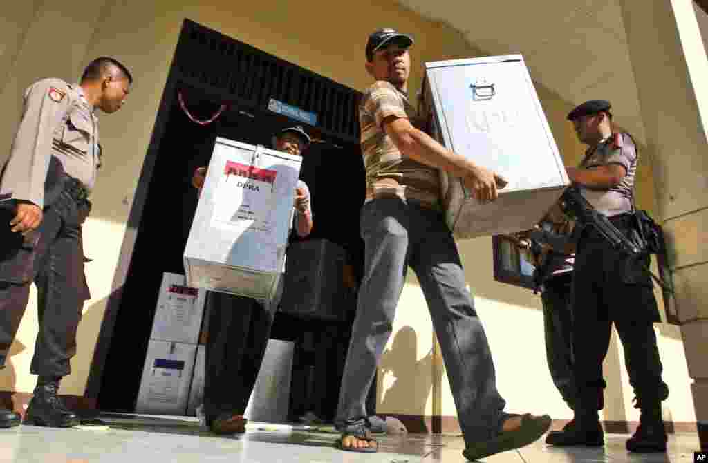 Armed police officers stand guard as election officials carry ballot boxes to be distributed to polling stations at a local government office in Banda Aceh, Indonesia, April 8, 2014. 